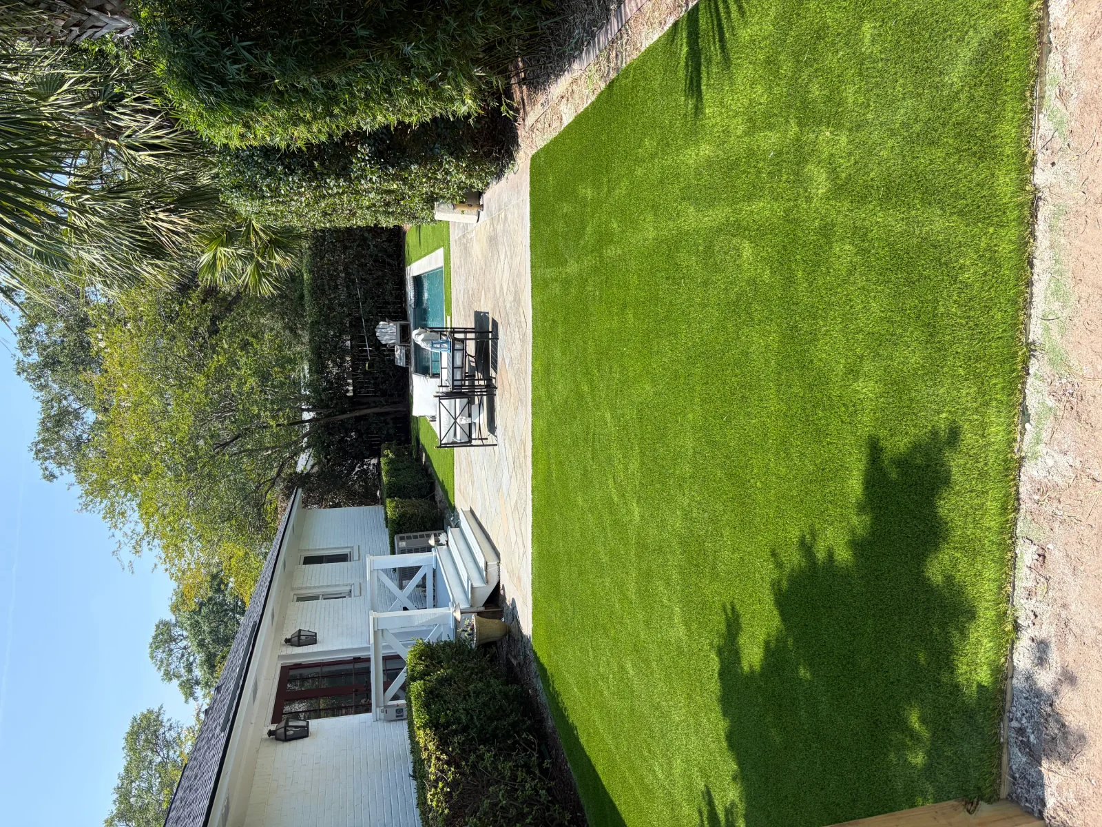Lush green residential lawn with mature trees and brick home exterior