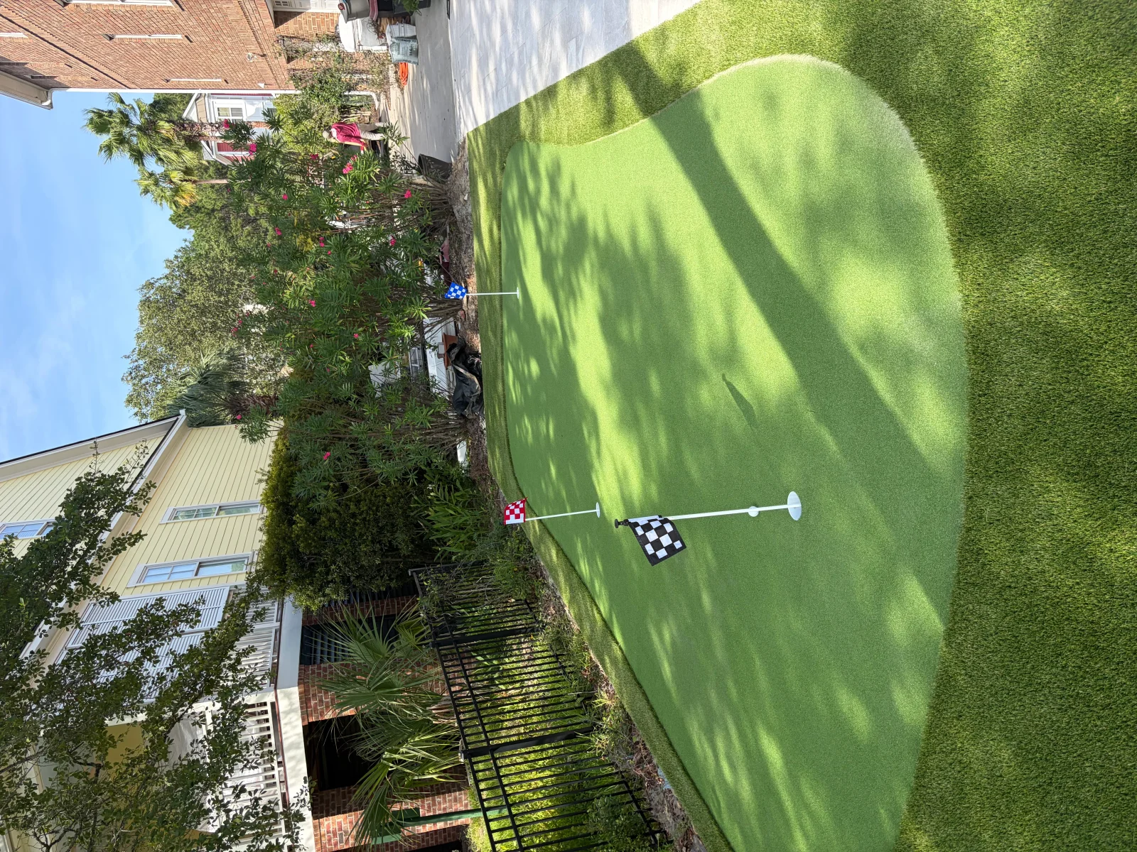 Synthetic turf golf green with practice flag in residential backyard setting